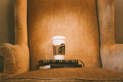 棕色织物扶手椅上的白色星巴克塑料杯